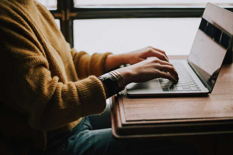 Person sitting at a desk in front of a laptop using the keyboard to shop online