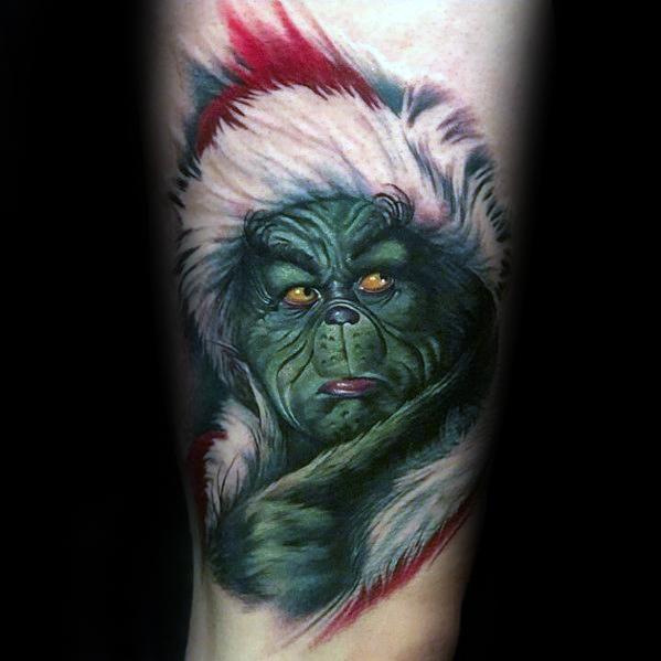 Realistic Christmas tattoo of the Grinch wearing a Santa hat, with an intense expression and detailed shading for a bold holiday design.