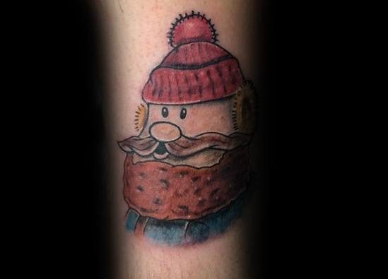 Christmas tattoo featuring a stylized Yukon Cornelius from *Rudolph the Red-Nosed Reindeer*, wearing a red beanie and winter scarf.