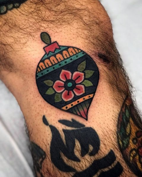 Vintage-style Christmas tattoo of a festive ornament with a bold floral design, geometric patterns, and rich traditional colors.