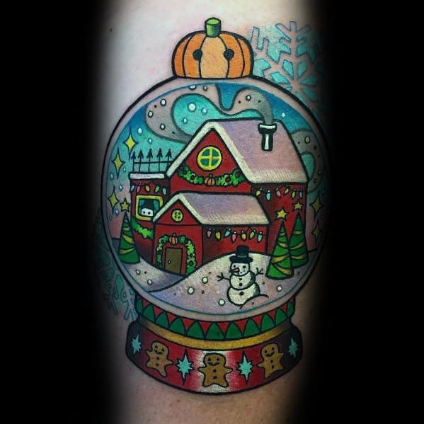 Colorful Christmas tattoo of a festive snow globe featuring a cozy holiday house, snowman, Christmas trees, and gingerbread-themed details.