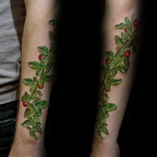 Realistic Christmas tattoo of a holly vine wrapping around the forearm, featuring detailed green leaves and red berries for a festive nature-inspired design.