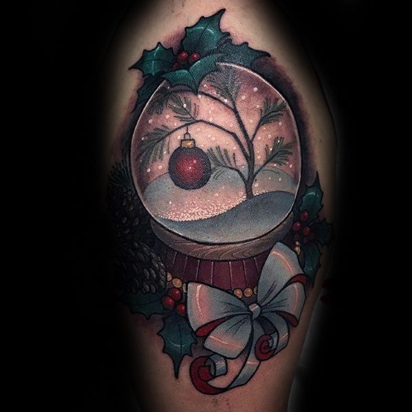 Christmas tattoo of a snow globe featuring a snowy tree branch with a red ornament, surrounded by holly, pinecones, and a festive ribbon bow.