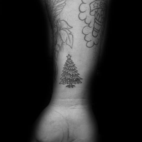 Small Christmas tree tattoo on the wrist with fine line details, ornaments, and a star on top, creating a subtle and festive design.