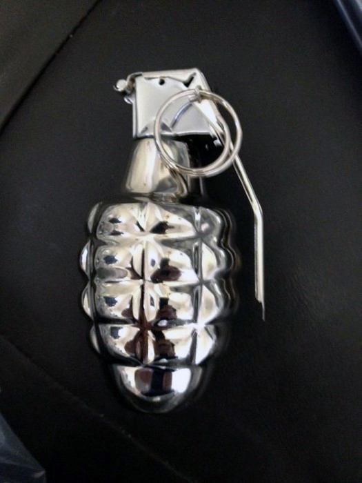 A shiny, silver grenade-shaped object resting on a dark surface