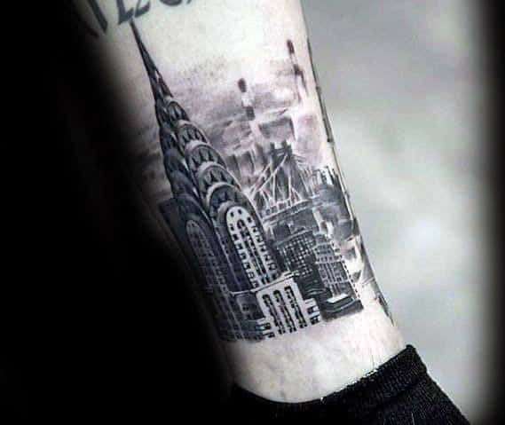 Black-and-grey Chrysler Building tattoo on the ankle with fine details and a cityscape background, creating a bold urban-inspired design.