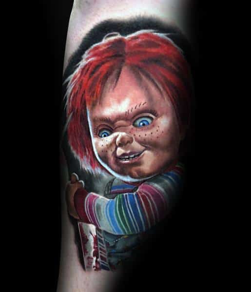 Realistic Chucky tattoo with glowing blue eyes, fiery red hair, and a bloodied knife, capturing his eerie and sinister expression.