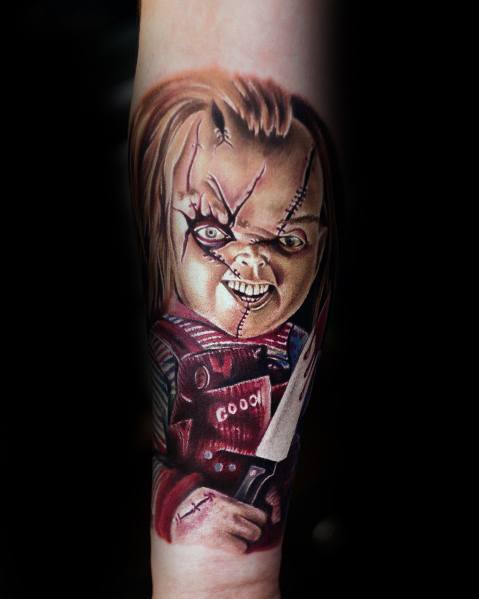 Realistic Chucky tattoo with sharp details, featuring his sinister grin, stitched face, and a bloodied knife for a chilling horror effect.