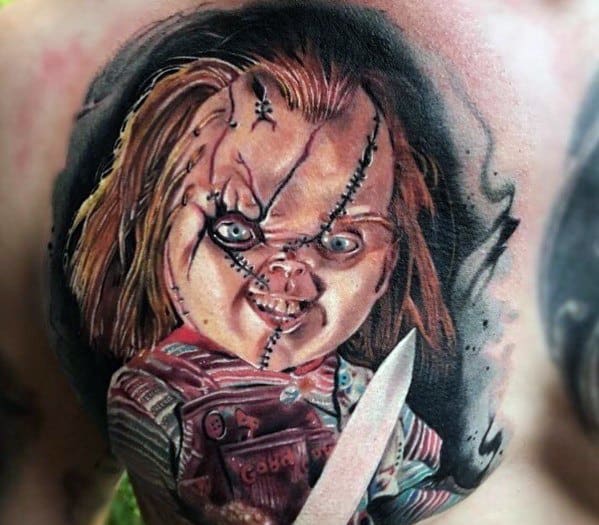 Realistic Chucky tattoo with intense shading, showing his sinister grin, stitched face, and a bloodied knife for a bold horror-themed design.