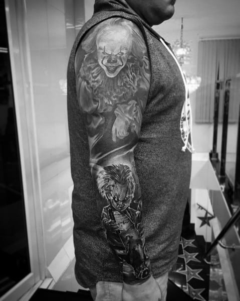 Black and grey horror sleeve tattoo featuring Pennywise and Chucky, with intense shading and realistic details for a chilling design.