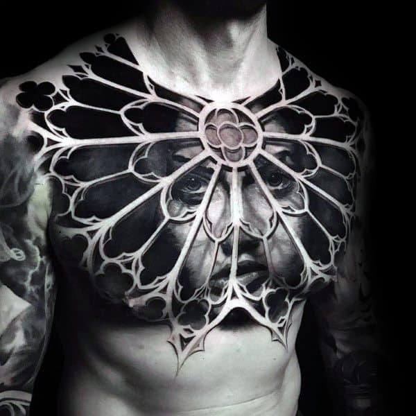 Gothic-style chest tattoo of a stained glass window with a haunting face behind it, symbolizing mystery, confinement, and hidden emotion.