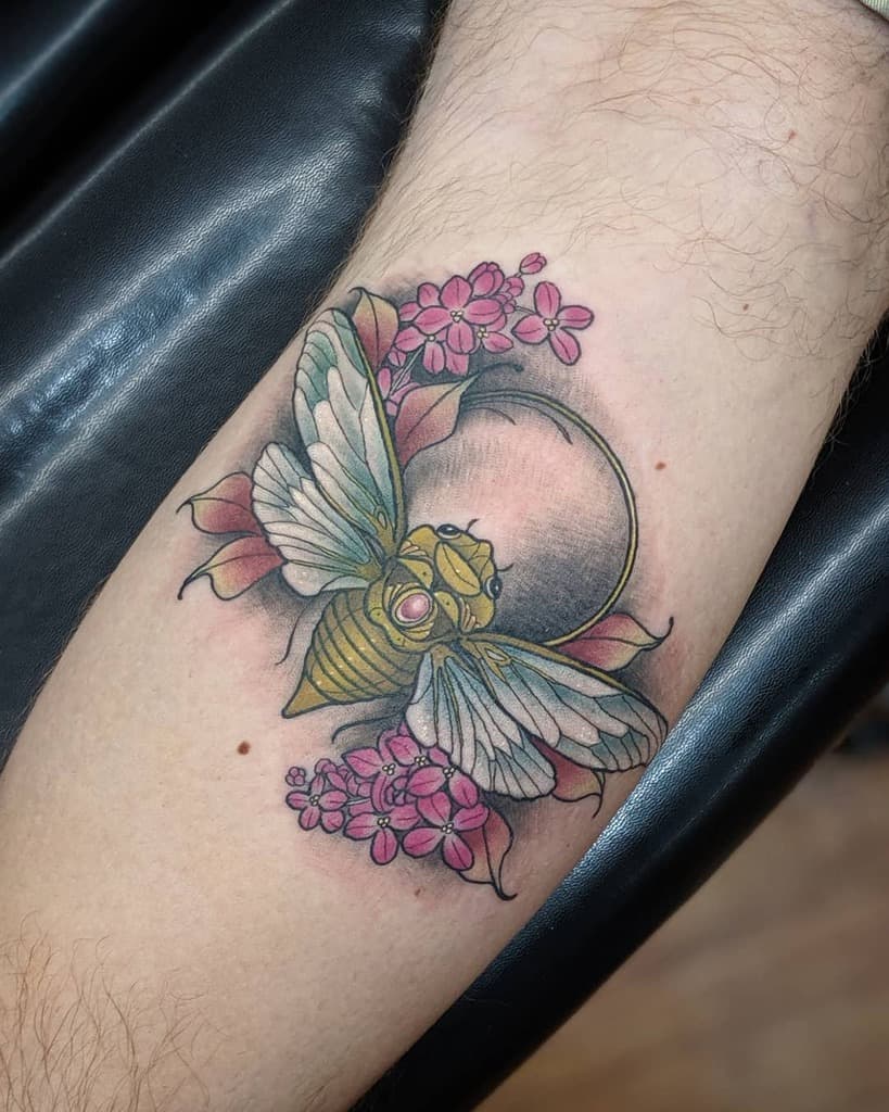 Tattoo of a cicada with detailed wings, surrounded by lilac flowers and a glowing moon, blending realism with neo-traditional style.