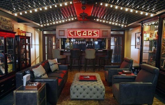 Cozy cigar lounge with leather seating, a bar, and a red "CIGARS" sign under warm string lights