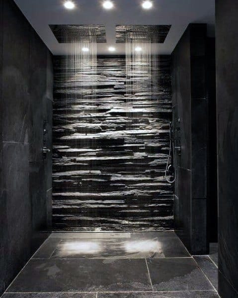 Luxurious shower with recessed ceiling lights and dual showerheads, featuring a striking textured black stone wall