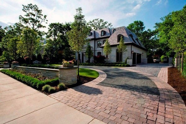 Circular driveway with a combination of brick pavers and gravel, bordered by landscaping features.