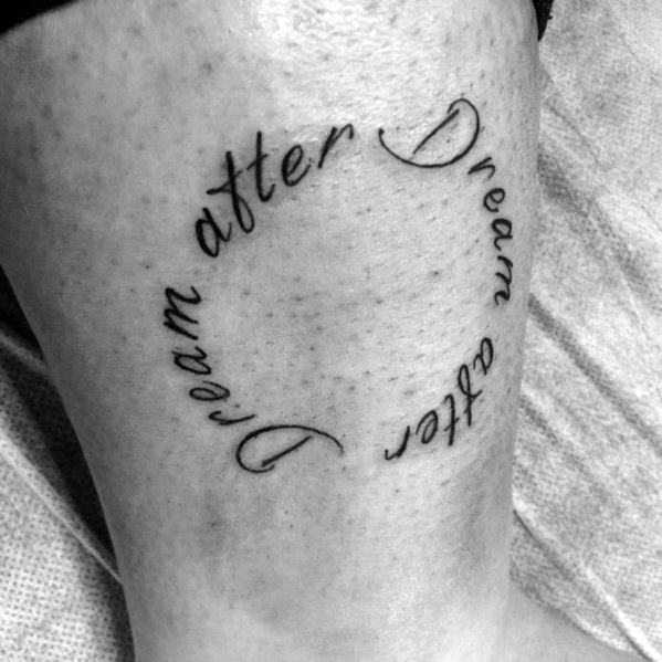Circular ankle tattoo with the words “Dream after Dream after Dream” written in elegant cursive script forming a loop.