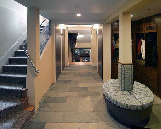 Basement with circular upholstered seating around pole, tiled flooring, and built-in storage units.