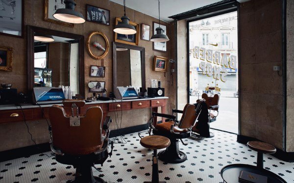 Classic barbershop with vintage chairs, tiled flooring, and large mirrors with ornate frames.