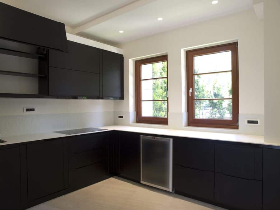 Classic kitchen with black cabinets and white countertops against a neutral backdrop.