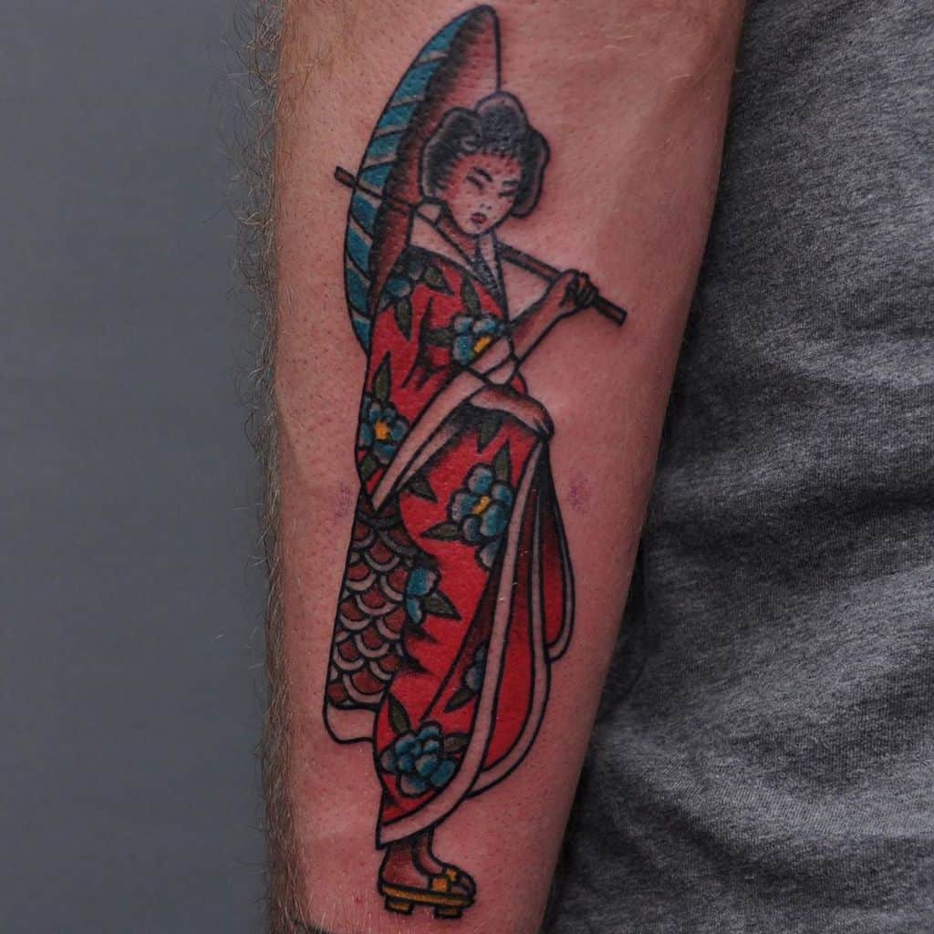 Traditional Japanese-style Geisha tattoo on the forearm, wearing a red floral kimono and holding a blue parasol with bold black outlines.