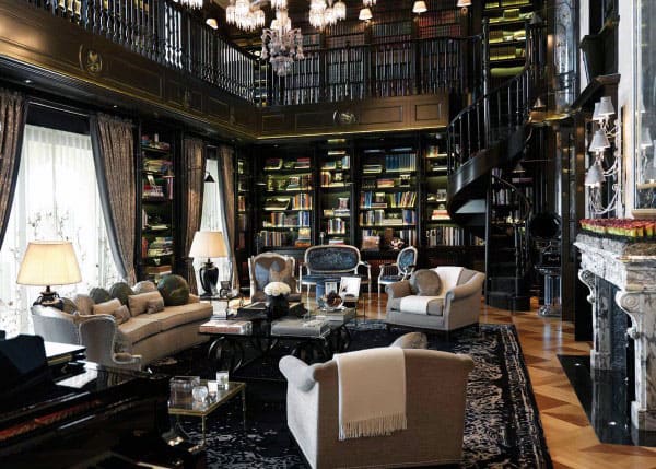 Luxurious library boasting high ceilings, spiral staircase, elegant seating, chandeliers, and a grand bookshelf wall