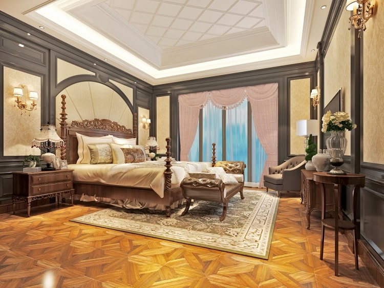 A luxurious master bedroom featuring a tray ceiling, classic wood furniture, elegant decor, and large windows, creating a serene and sophisticated atmosphere