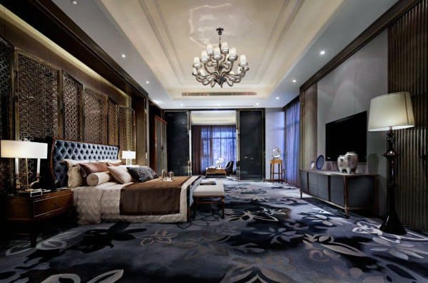 Elegant luxury bedroom with chandelier, plush carpet, and modern decor accents.