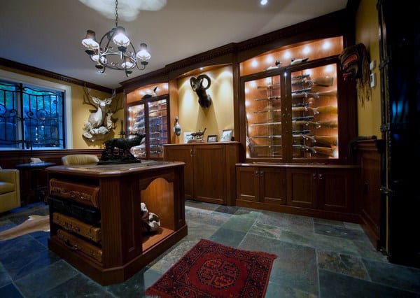 Elegant gun room with wooden cabinets, trophy mounts, and a chandelier for a sophisticated ambiance.