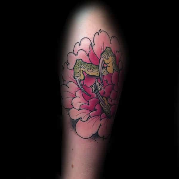 Tattoo of a pink lotus flower with green claws emerging, inked on an arm