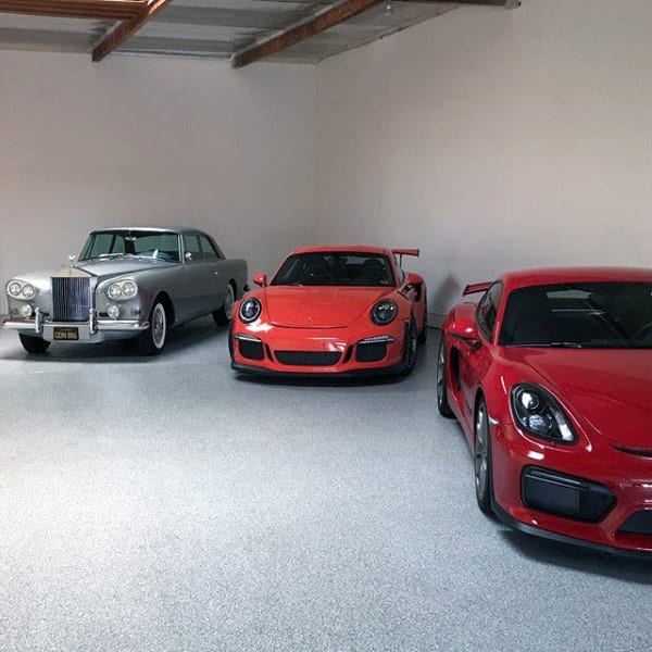 Clean and minimalist garage showcasing a vintage Rolls-Royce and sleek Porsche models.