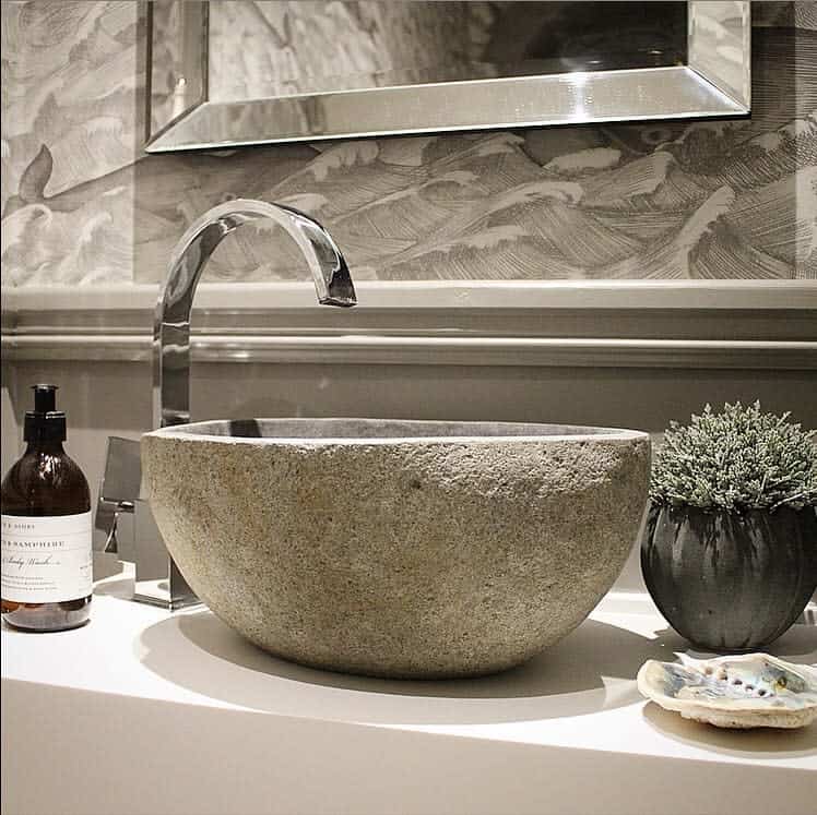 Modern bathroom with stone sink, chrome faucet, and decorative plant on the countertop.