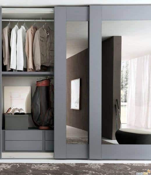 Modern closet with sliding mirror doors, clothes hanging inside