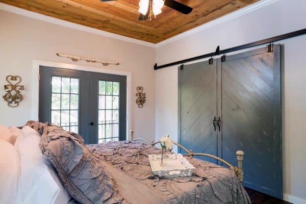 Rustic bedroom with a sliding barn door closet in gray, wood accents, and French-style double doors