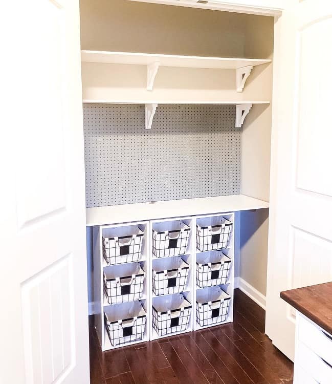 Reach-in closet with pegboard wall and cubby storage baskets.