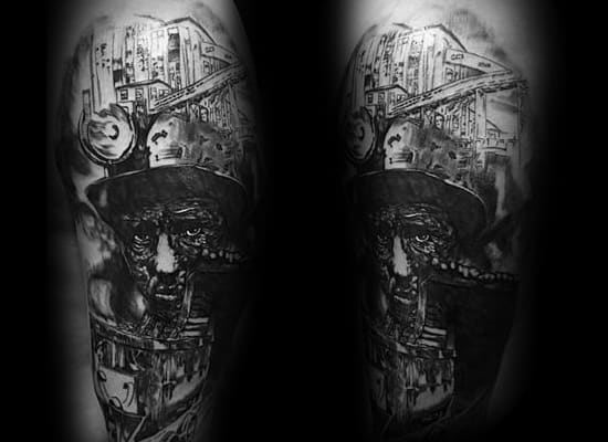 Black and grey tattoo of a miner's face blending into industrial coal mining structures with detailed shading and contrast.