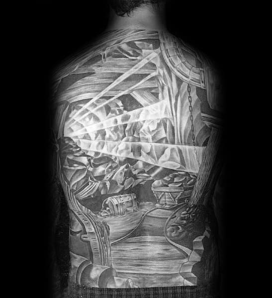 Full back tattoo in black and grey showing a detailed underground coal mine tunnel with beams of light and mining equipment.