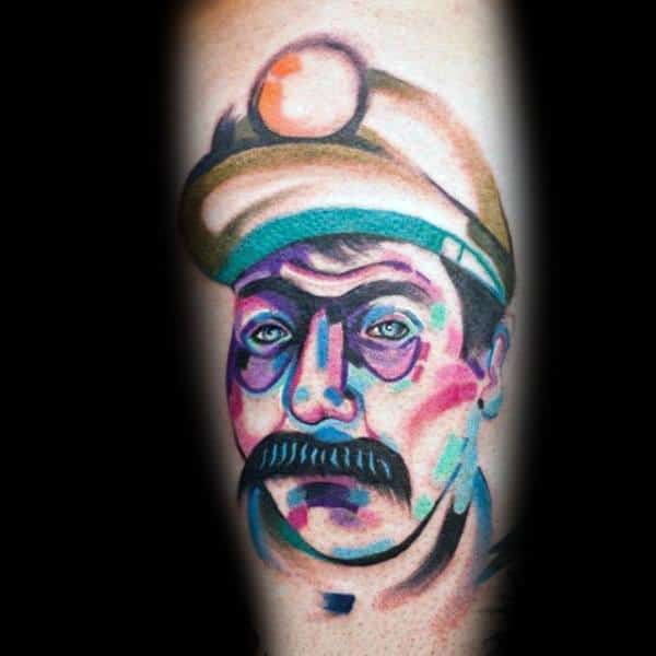 Vibrant abstract tattoo of a miner’s face with a helmet and headlamp, done in bold colors and expressive brushstroke style.