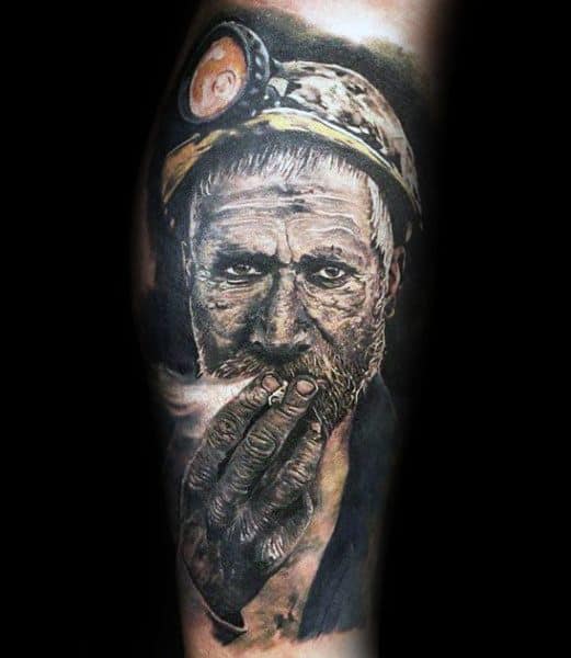 Hyper-realistic tattoo of an older coal miner with a helmet and headlamp, shown smoking with a weathered, expressive face.