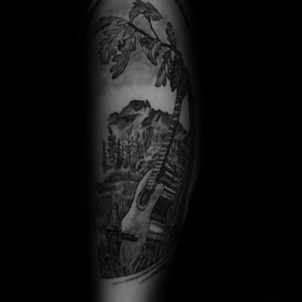Black and grey scenic tattoo featuring a Coca-Cola bottle, acoustic guitar, and mountain landscape, creating a peaceful, nature-inspired design.