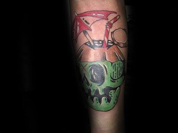 Creative tattoo of a green skull-shaped coconut drink with a red umbrella, straw, and garnish, inked on the forearm.