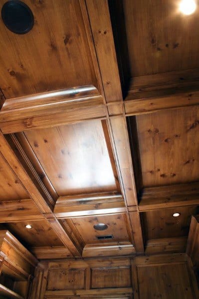 Coffered ceiling with rich wood finish and recessed lighting in a warm interior space.