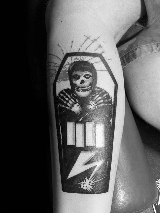Black Flag bars tattooed on a coffin design featuring a skeleton figure in striped clothing, with a lightning bolt and splatter detail below.