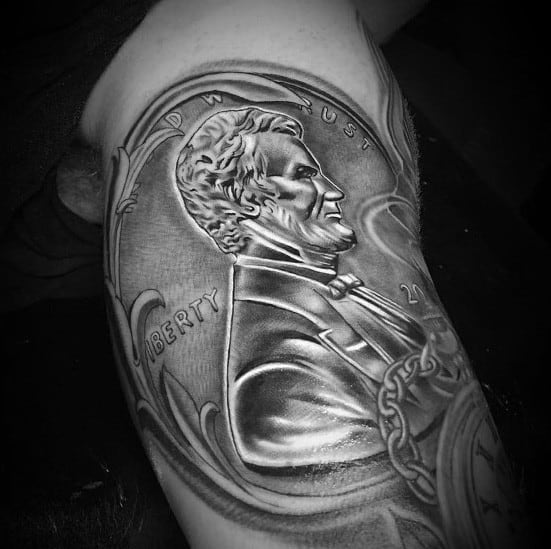 Intricate tattoo of a Lincoln coin with bold shading and ornate details, creating a striking three-dimensional effect on the arm.