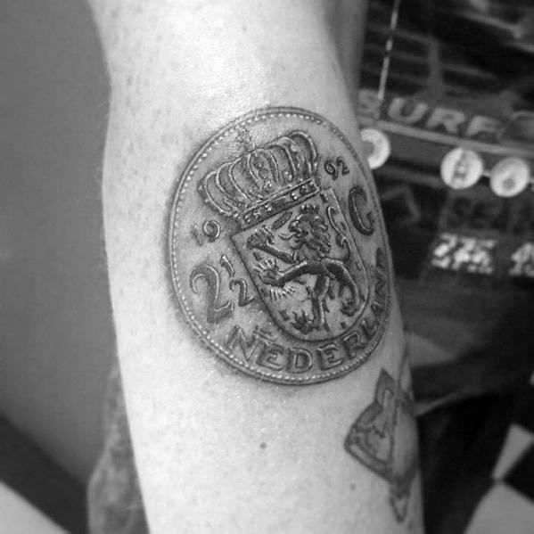 Realistic tattoo of a 2½ Gulden Dutch coin featuring a crowned lion and 'Nederland,' with detailed shading for a three-dimensional effect.
