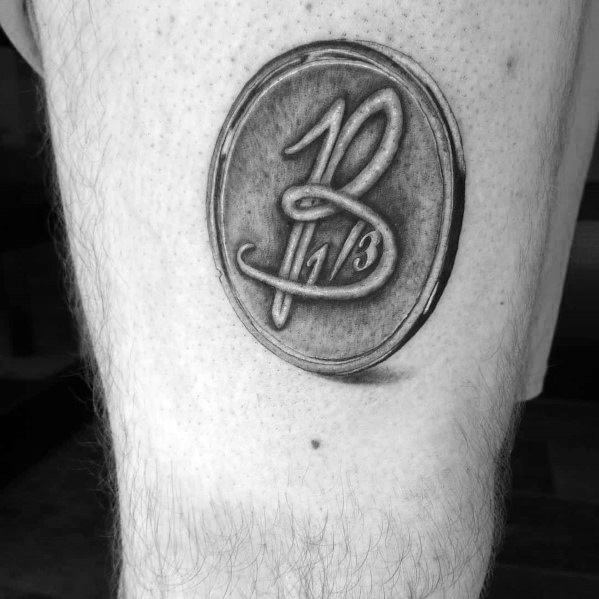 Realistic tattoo of an old 10 1/3 coin on the thigh, featuring intricate shading and a worn, antique look for a vintage aesthetic.