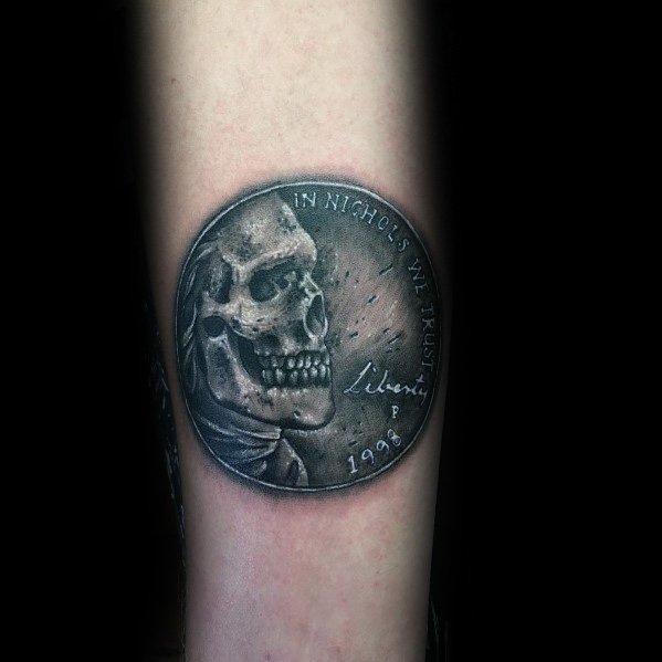 Dark, detailed tattoo of a modified coin featuring a skeletal figure in place of a historical portrait, creating a striking and eerie design.