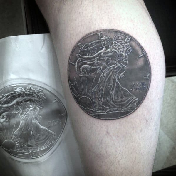 Realistic tattoo of a Walking Liberty half-dollar coin on the leg, featuring intricate shading for a detailed and lifelike effect.