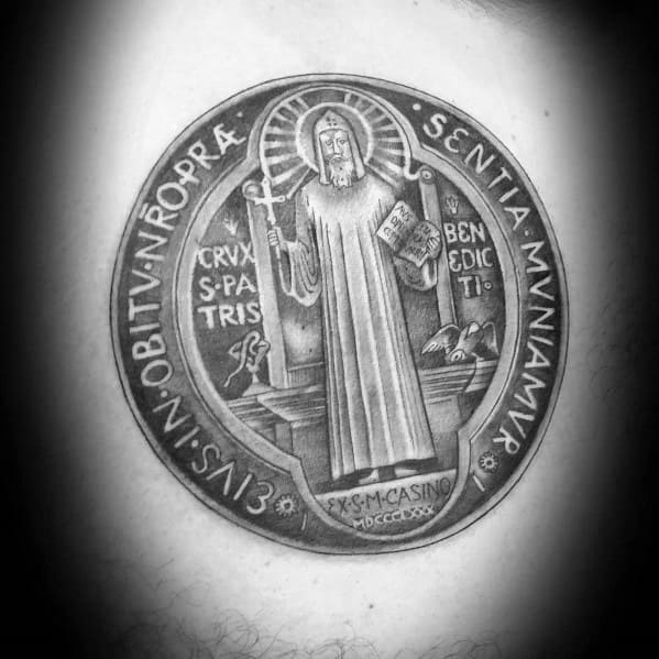 Realistic tattoo of a Saint Benedict medal featuring intricate details, religious symbols, and Latin inscriptions for a sacred design.
