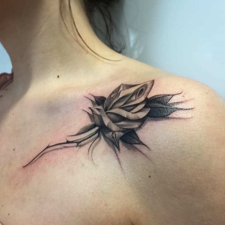 A black and gray rose tattoo on a shoulder