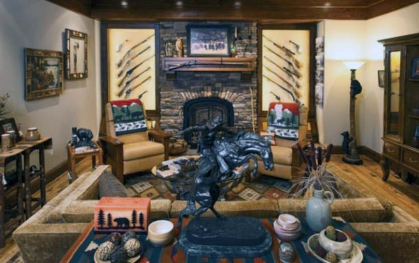 Rustic gun room with a cozy seating area, stone fireplace, and displayed firearms.